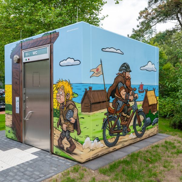 Wikinger Graffiti auf einem Beton-WC in Schleswig mit Rapsfeld und Comic-Motiven