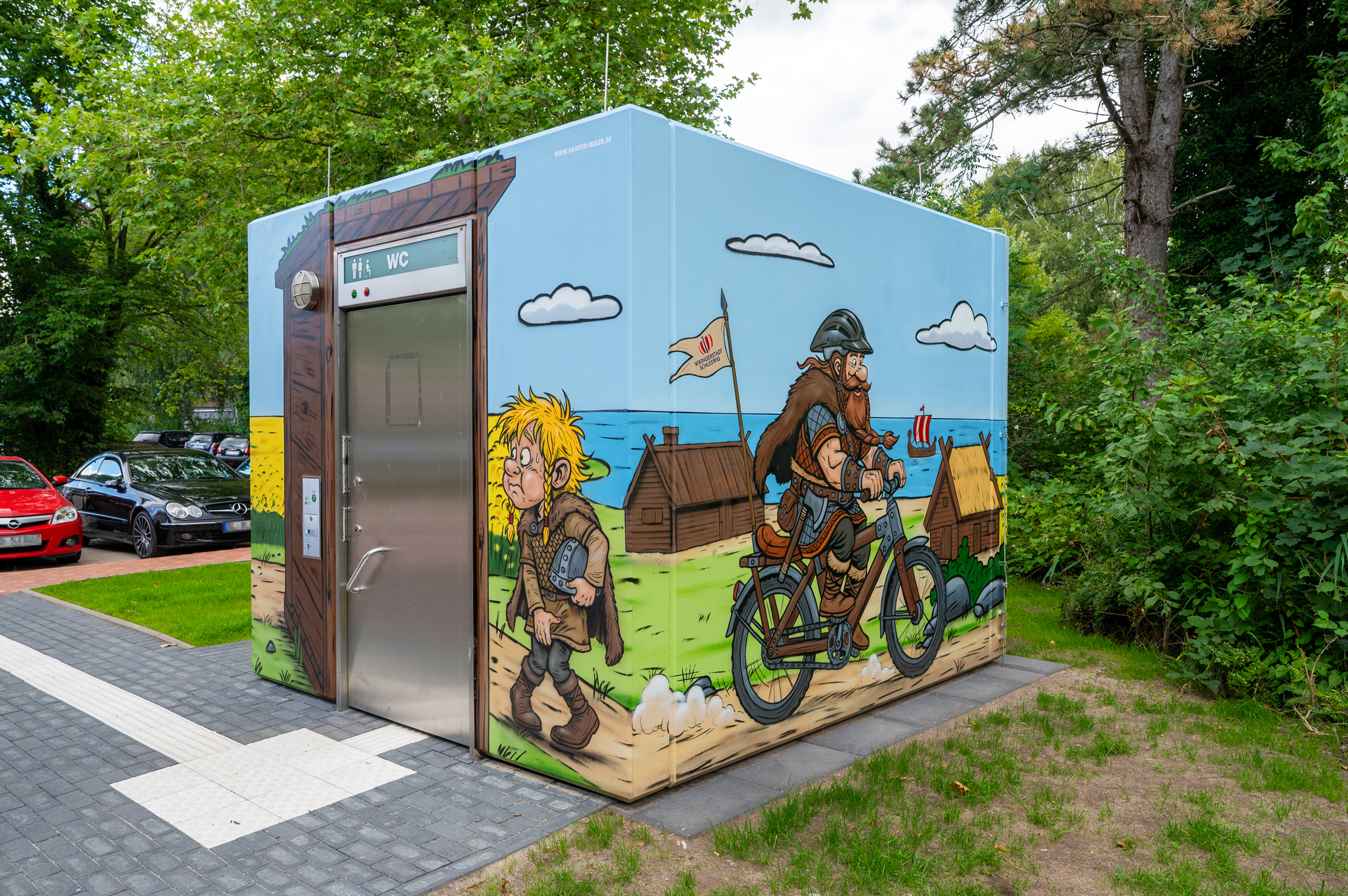 Wikinger Graffiti auf einem Beton-WC in Schleswig mit Rapsfeld und Comic-Motiven