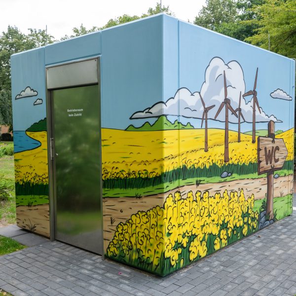 Wikinger Graffiti auf einem Beton-WC in Schleswig mit Rapsfeld und Comic-Motiven